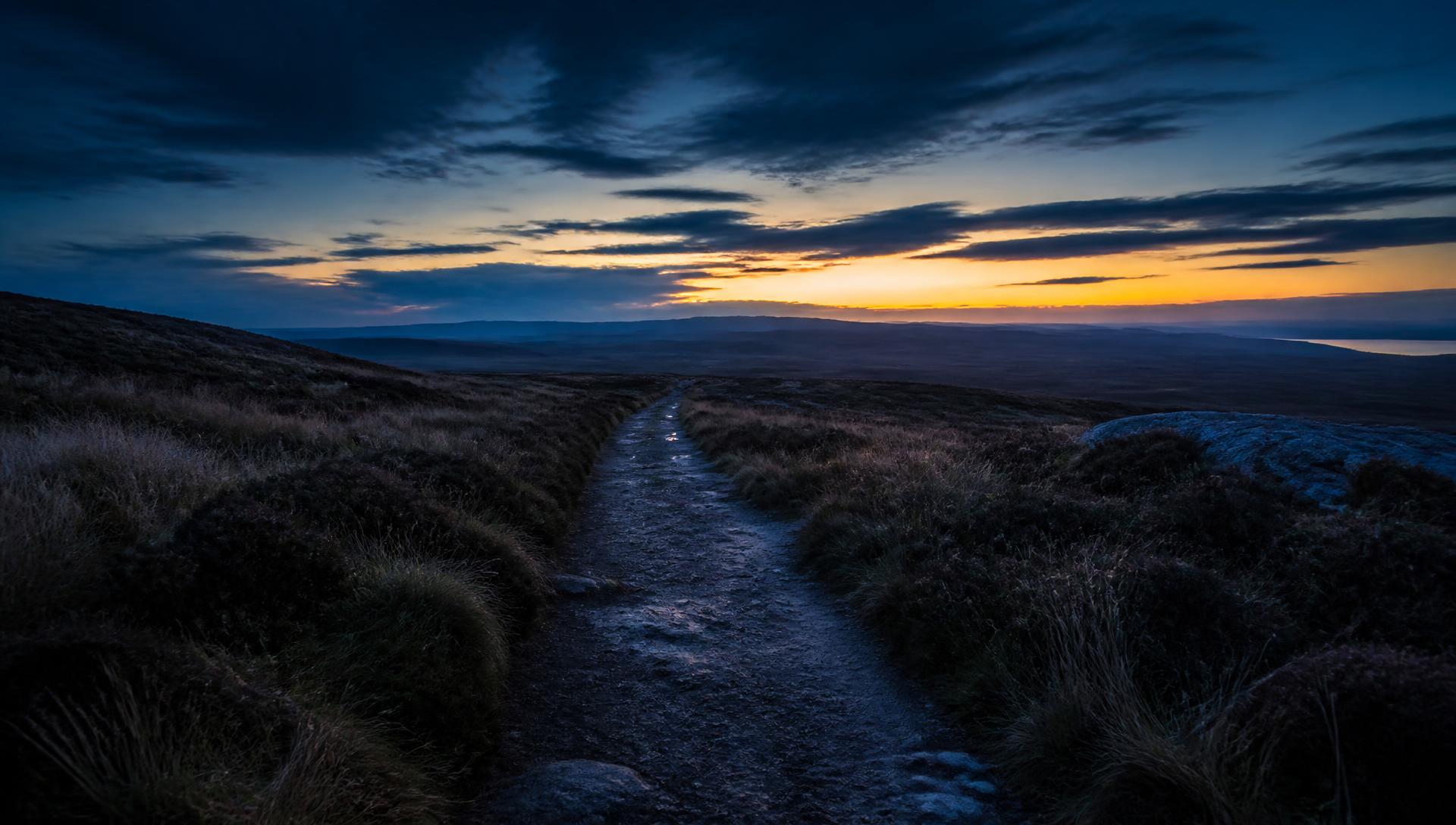 A quiet path leading towards a distant horizon at dusk